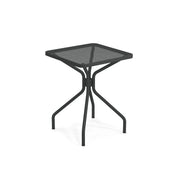 The Cambi Table is a small, square, black metal outdoor table featuring a mesh top and four curved legs meeting at a central support. Its minimalist, modern design with a matte finish suits both indoor and outdoor spaces.