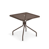 The Cambi Table features a brown metal frame with a square mesh top and four curved legs. Its central umbrella hole and modern design make this outdoor/indoor table a versatile, stylish choice. Plain white background highlights its structure and color.
