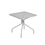 The Cambi Table is a square, light gray mesh top table with four curved legs meeting at a central point below the surface. Featuring a circular hole for an umbrella, this outdoor/indoor table stands out against the plain white background.