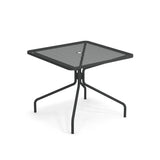 The Cambi Table is a modern, minimalist black metal square table with a mesh top, four outward-angled legs, and a central umbrella hole. Perfect for outdoor/indoor use, it's shown on a white background.