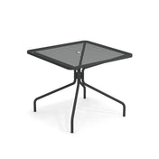 The Cambi Table is a modern, minimalist black metal square table with a mesh top, four outward-angled legs, and a central umbrella hole. Perfect for outdoor/indoor use, it's shown on a white background.
