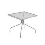 The Cambi Table is a square, light gray outdoor/indoor table with a mesh top, rounded corners, and simple tubular legs that angle outward. A small circular hole in the center allows for an umbrella pole. The design is minimalist and modern.