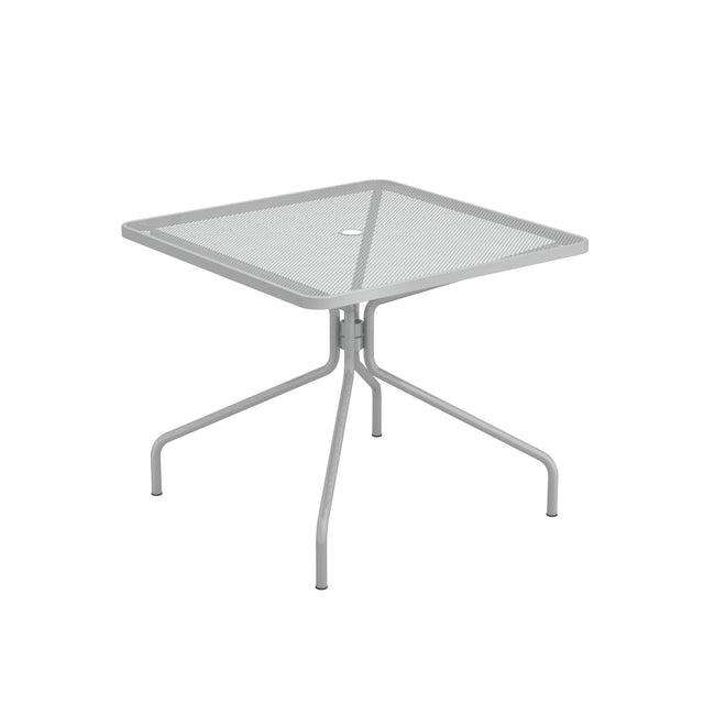 The Cambi Table is a square, light gray outdoor/indoor table with a mesh top, rounded corners, and simple tubular legs that angle outward. A small circular hole in the center allows for an umbrella pole. The design is minimalist and modern.