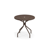 A round, brown Cambi Table with a mesh top and a central hole, supported by four bent legs that connect near the base. This outdoor indoor table is shown on a plain white background.