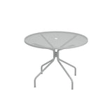 The Cambi Table is a round, gray metal outdoor/indoor table featuring a mesh top and four angled legs converging at the center. Its minimalist, modern design includes a small hole in the middle, perfect for an umbrella. Shown on a plain white background.