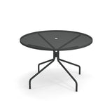 A round, black Cambi Table with a mesh top and a central hole for an umbrella. This outdoor table features slender, angled legs that branch out for stability, casting soft shadows on a white background.
