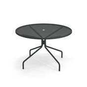 A round, black Cambi Table with a mesh top and a central hole for an umbrella. This outdoor table features slender, angled legs that branch out for stability, casting soft shadows on a white background.