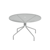 The Cambi Table is a round, metal mesh top outdoor table with a light gray finish and four gently curved legs extending outward from a central support. Its minimalist, modern design features a center hole for an umbrella, perfect for any patio setting.