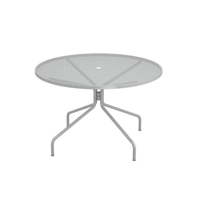 The Cambi Table is a round, metal mesh top outdoor table with a light gray finish and four gently curved legs extending outward from a central support. Its minimalist, modern design features a center hole for an umbrella, perfect for any patio setting.