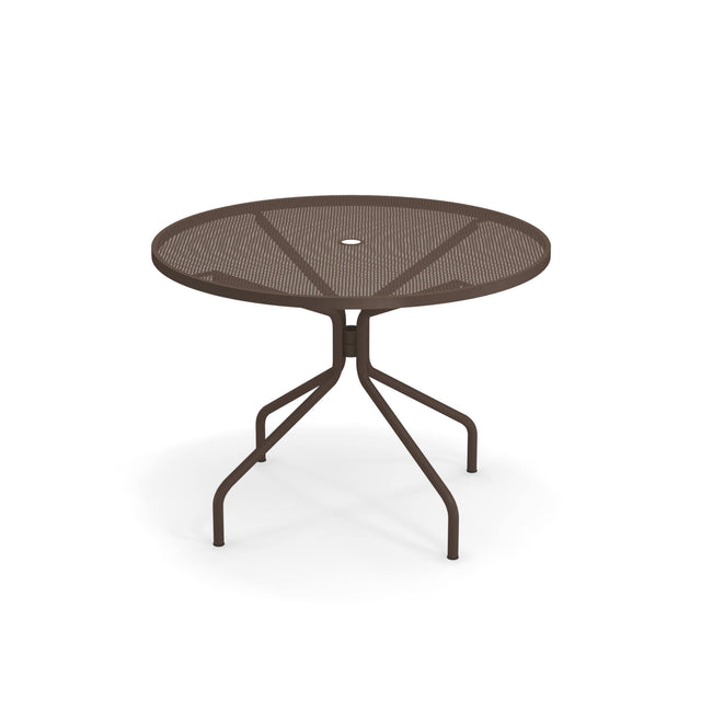 The Cambi Table is a round, metal outdoor table with a mesh top and four angled legs, all in dark brown. It features a small circular hole in the center for an umbrella and is set against a plain white background.