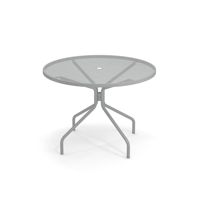 A round outdoor table with a mesh top and a central hole for an umbrella. Its four angled legs curve outward and then downward, ensuring stability on any patio. The background is plain white for a clean, classic look.