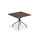 A square brown outdoor indoor table with a central hole in the tabletop, supported by four legs branching out from a single central column. This minimalist, modern piece is made in Italy and set against a white background.