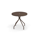 A round, dark brown solid steel outdoor table with a central hole on the tabletop, supported by four angled legs that connect to a central vertical post. The table stands on a white background with a faint shadow beneath it.