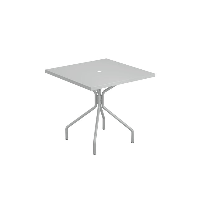 A square, light gray solid steel table with four legs that curve outward from a central support. The tabletop has a small circular hole in the center, possibly for an umbrella. Suitable as an outdoor indoor table. The background is plain white.