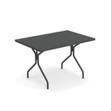 A rectangular black folding table with a smooth surface and sturdy solid steel legs, slightly angled for stability. The minimalist solid steel table is shown against a plain white background.
