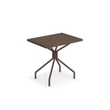 A modern, rectangular brown indoor/outdoor table with a flat top and four slender, angled legs that meet at a central point beneath the tabletop, creating a geometric, minimalist design against a white background.