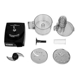A disassembled Waring food processor set on a white background, showing the 1.7 liter motor base, clear plastic bowl, lid with feed tube, pusher, S-blade, dough blade, slicing disc, and shredding disc—all neatly arranged and separated.