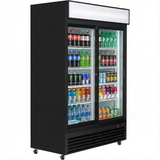 A commercial refrigerated merchandiser displays various drinks, including bottled water, sodas, sports drinks, and canned beverages, organized on multiple shelves. The large-capacity black unit has wheels and a blank white sign above the doors.