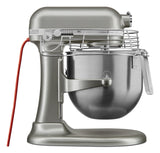 A silver KitchenAid Commercial Stand Mixer with an 8 quart bowl and safety guard features PowerCore technology, a red power cord, adjustable speed dial, and sturdy base, with the bowl securely locked beneath the mixing head.
