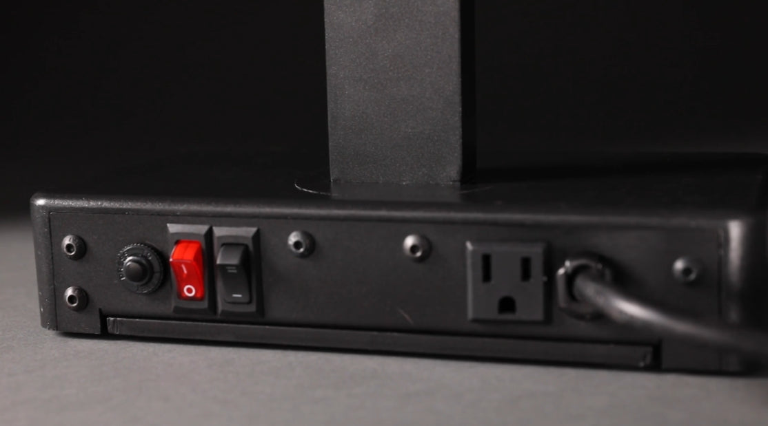 A close-up of the back panel of an NSF-certified electronic device shows two toggle switches—one red and one black—a round connector, a standard electrical outlet, and a power cord plugged in, all mounted on a matte black surface.