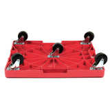 A red, rectangular Krowne dolly is shown upside down, displaying five black swivel caster wheels attached at the edges and center. The dolly has a textured, ribbed undersurface for strength and a shallow recessed area on top.