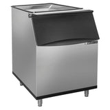 A stainless steel ice storage bin with a black, slanted front door and four metal legs. The unit has a clear, hinged top lid, 470 lbs ice capacity, and is labeled MAXX ICE on the front—sleek and functional for restaurant or bar use.