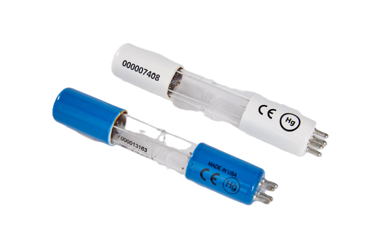 Two UV Replacement Bulb germicidal lamps with cylindrical glass bodies; one has a white end cap, the other blue. Both have metal prongs, CE markings, Hg symbols, serial numbers like K00425, and are labeled Manitowoc Made in USA on a white background.