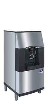 A stainless steel, AHRI certified commercial vending ice dispenser with a black accent panel, angled front, water and ice spouts, and a drip tray beneath. It stands on four short legs and features a blue manufacturer’s logo on the lower right front.