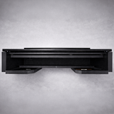 A black, wall-mounted floating desk with two pull-out drawers, viewed from the front against a light gray background. The minimalist design features clean lines, no visible hardware, and complements spaces with a collapsible bar system like the NomadBar Mobile.