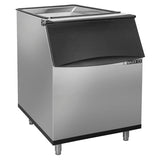 A commercial Maxx Ice storage bin with a black hinged lid and 580 lbs ice storage capacity. It stands on four metal legs, features a slanted front for easy access, and offers a modern, functional design perfect for any setting.