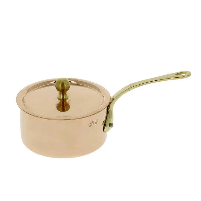 A De Buyer Copper Saucepan with a matching copper lid features a brass handle and knob. Its mirror polishing and round shape create a striking look, beautifully displayed against a plain white background.