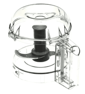 A transparent Cryst Cutter food chopper with a round base, black spinning blade inside, and plunger handle on top. The domed lid and side rectangular compartment resemble features of the popular Robot Coupe R2 Dic Attachment.