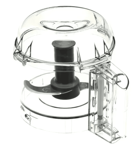 A transparent Cryst Cutter food chopper with a round base, black spinning blade inside, and plunger handle on top. The domed lid and side rectangular compartment resemble features of the popular Robot Coupe R2 Dic Attachment.