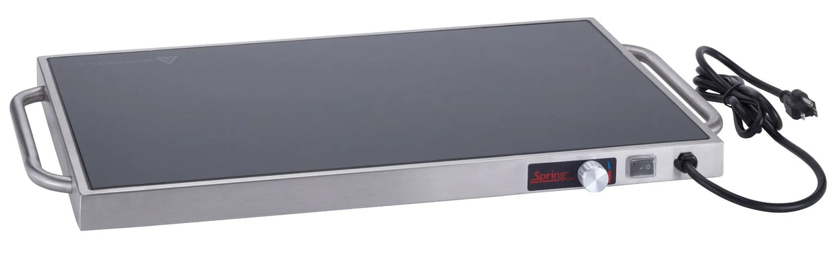 A rectangular warming tray with a tempered glass surface, stainless steel body, two side handles, a control knob for temperature settings, an on/off switch, and a black power cord with plug attached on the right side.