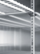 Close-up of a metal shelving unit with numbered holes along the vertical support, adjustable for height—ideal for use within a pharma-lab all-freezer or commercial reach-in freezer. The image is in grayscale, showing part of a metal shelf above and reflective surfaces in the background.