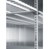 Close-up of a metal refrigerator interior showing adjustable shelf supports, metal rails with regularly spaced slots, and a white wire shelf. The surfaces are clean and reflective, highlighting the industrial, utilitarian design typically found in a commercial refrigerator.