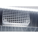 A close-up of a white plastic vent with a grid pattern secured by two screws on the reflective metallic surface of a commercial refrigerator, illuminated by bright white light from above, creating light streaks and reflections.