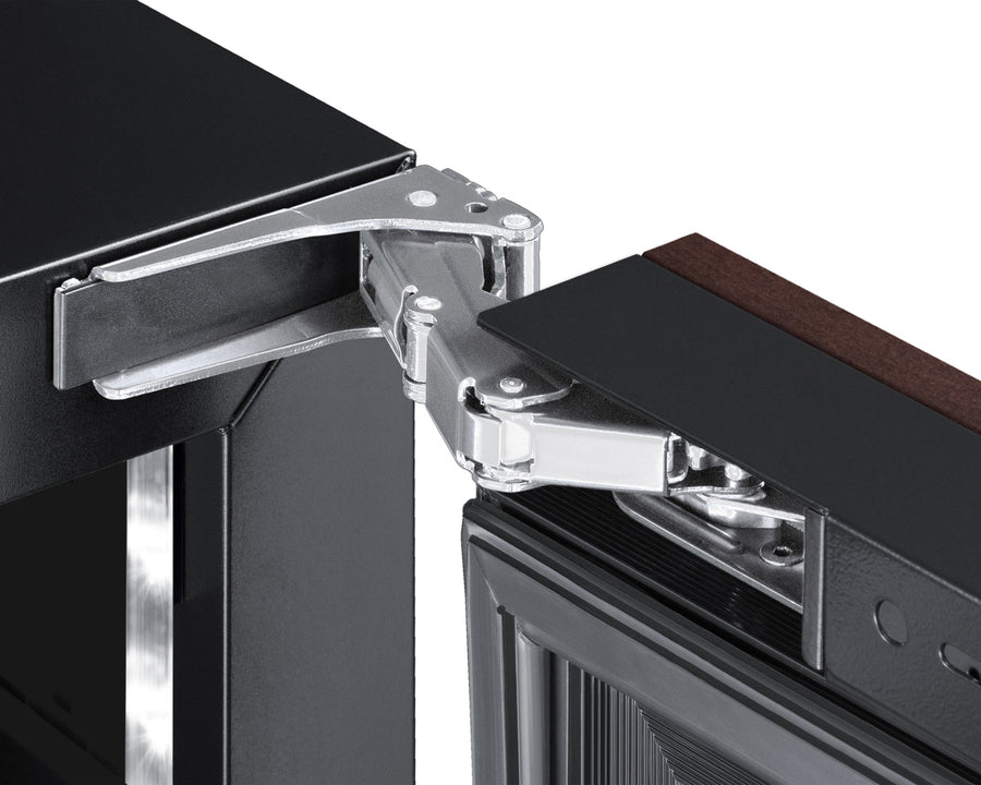Close-up of a robust, silver hinge connecting a dark cabinet frame to a panel ready door. The door features a glass panel and dark wood trim—typical of a stylish commercial beverage center or premium undercounter unit.