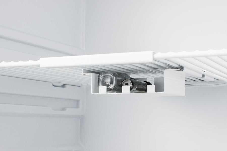 A close-up of a medical refrigerator shelf shows an inverted bottle holder attached underneath, securely holding two glass bottles horizontally. The fridge interior is clean, with white shelves and a minimalist design.