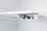 A close-up of a medical refrigerator shelf shows an inverted bottle holder attached underneath, securely holding two glass bottles horizontally. The fridge interior is clean, with white shelves and a minimalist design.