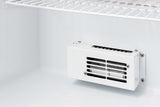 Close-up of a white, metal vent cover with horizontal slats, mounted on the back interior wall of a pharmaceutical compact refrigerator. Above is a white wire shelf. The scene is brightly lit, showing clean and empty fridge space.