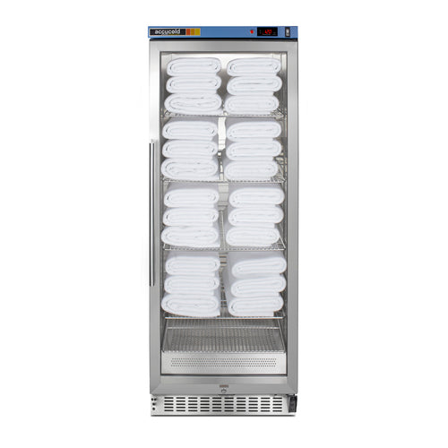 A tall, stainless steel glass-door cabinet holds neatly stacked white towels on four shelves. Using passive heating technology, this blanket warmer ensures towels are always at the perfect temperature. The digital display on the top front panel shows the temperature, while vents at the bottom and a vertical handle on the left side add to its sleek functionality.