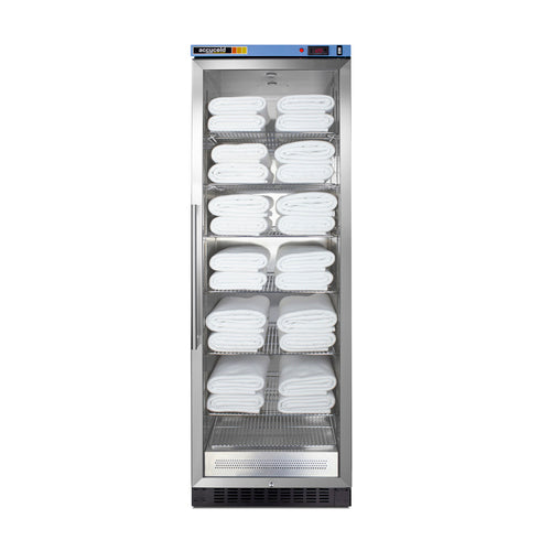 A tall, stainless steel towel warmer with a glass door, featuring adjustable shelves and displaying six tiers stacked neatly with multiple rows of folded white towels, against a plain white background.