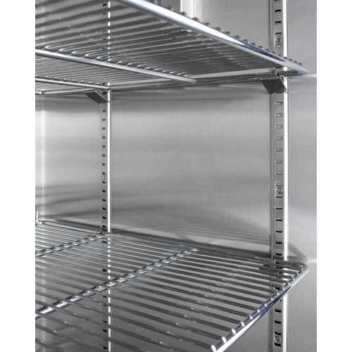 Close-up of empty metal wire adjustable shelves inside a stainless steel refrigerator or storage unit, with support tracks visible on the side walls. The shelves reflect light, showing a clean and organized, industrial appearance reminiscent of equipment found in a blanket warmer that utilizes passive heating technology.