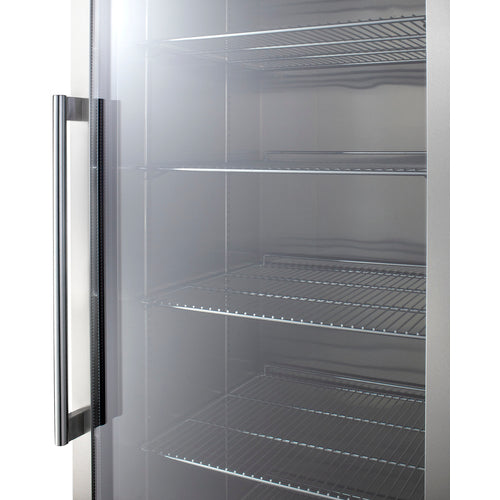 A close-up of an empty commercial refrigerator with a glass door, metal handle, and several adjustable shelves inside. The stainless steel interior reflects light, and the shelves are evenly spaced and clean.