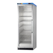 A tall, upright stainless steel commercial refrigerator with a glass door and five adjustable shelves stands empty against a white background. A blue panel with buttons and a display is on top of the door.
