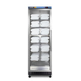 A tall, stainless steel towel warmer cabinet with a glass door shows neatly stacked, folded white towels on multiple adjustable shelves inside. The cabinet stands on four small wheels and has control buttons on the top front panel. Incorporating passive heating technology, this blanket warmer ensures your linens remain perfectly warm and ready for use.