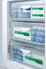 Three transparent freezer drawers contain boxes labeled Varicella Virus Vaccine Live and Store Frozen, along with several blue cold packs. The drawers are organized, and the vaccine boxes are white with green and yellow labels, kept neatly in an Accucold Medical Freezer. This undercounter all-freezer is ADA compliant, ensuring reliable storage within a medical setting.