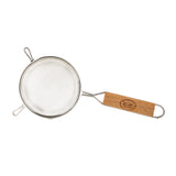 A fine mesh strainer with a round sieve and two support hooks on one side. It features a wooden handle with an engraved logo and a metal loop for hanging, photographed on a white background.