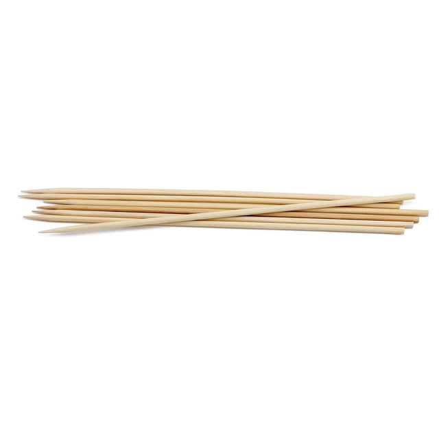 A small pile of TableCraft bamboo skewers lies on a white background. The 10 inch skewers are thin, cylindrical, light beige in color, and have sharp pointed tips for grilling or holding together pieces of food.